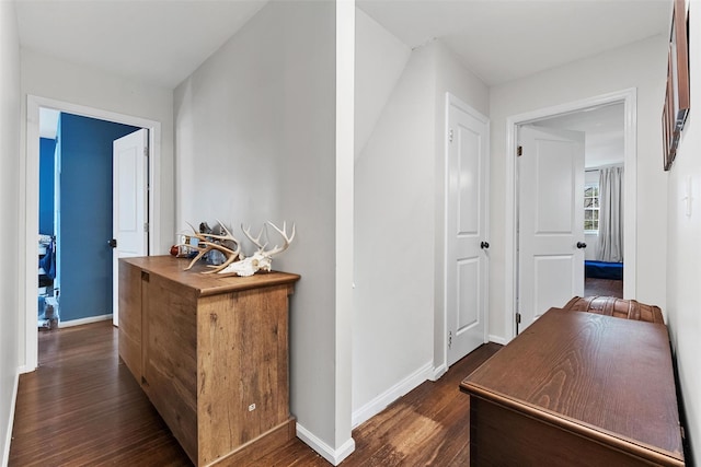 hallway featuring dark wood-style flooring and baseboards
