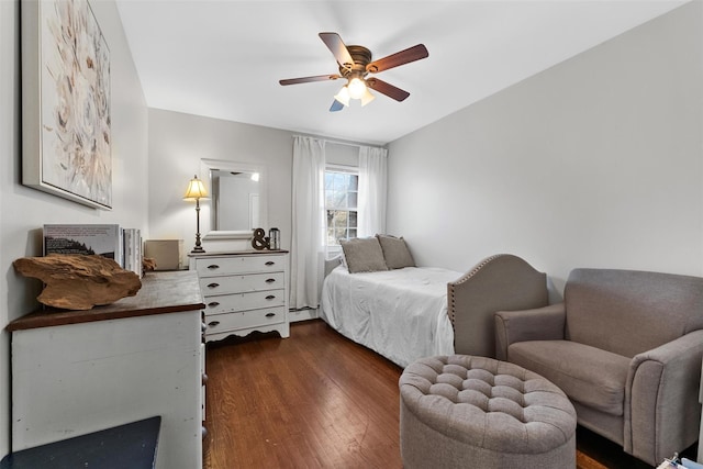 bedroom featuring a ceiling fan, a baseboard heating unit, and dark wood-type flooring