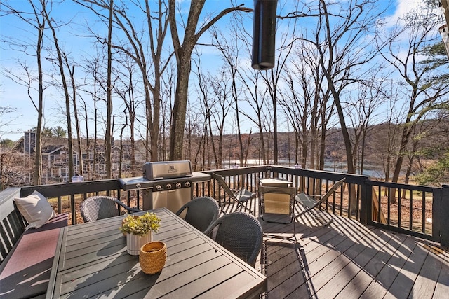 wooden terrace with a water view, grilling area, and outdoor dining space