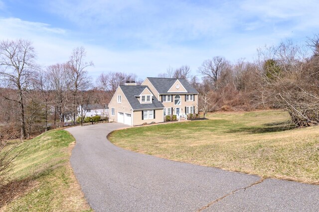 shingle-style home with driveway, a front lawn, a porch, a garage, and a chimney