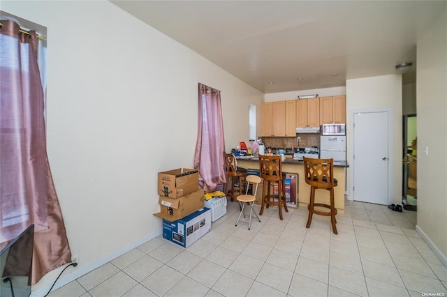 3440 Fulton St, Brooklyn, NY 11208 - kitchen with dark countertops, tasteful backsplash, light brown cabinets, under cabinet range hood, and a peninsula