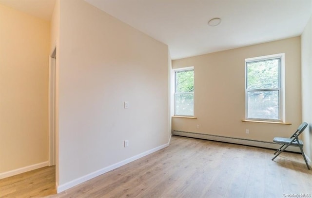 empty room with a wealth of natural light, light wood-type flooring, baseboards, and baseboard heating