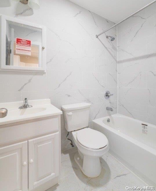 full bath with tile walls, toilet, vanity, and shower / bath combination
