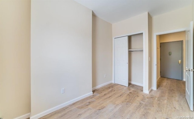 unfurnished bedroom featuring a closet, baseboards, and wood finished floors