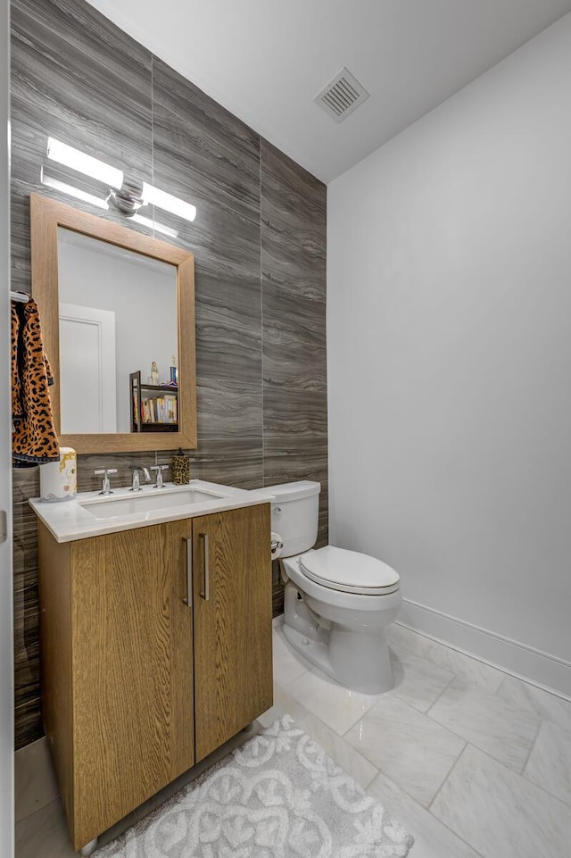 100 Garvies Point Rd Unit 1237, Glen Cove, NY 11542 - bathroom with toilet, vanity, tile walls, baseboards, and marble look tiles