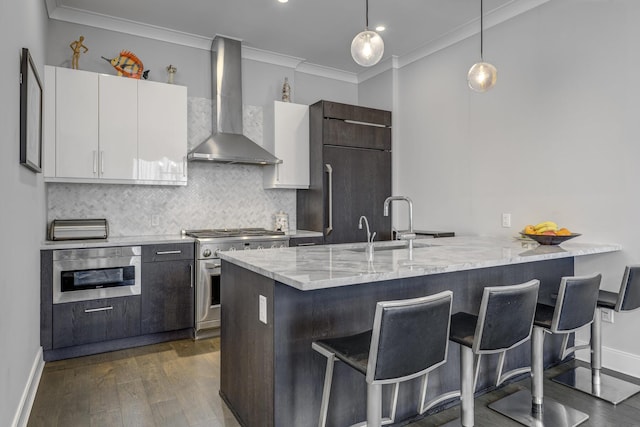 100 Garvies Point Rd Unit 1237, Glen Cove, NY 11542 - kitchen featuring wall chimney exhaust hood, high end stove, a peninsula, a breakfast bar area, and ornamental molding