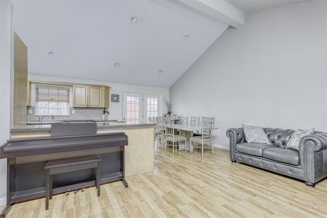 interior space with high vaulted ceiling, light wood-style flooring, beamed ceiling, and plenty of natural light