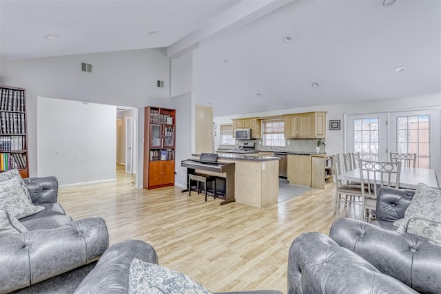 living room with beamed ceiling, visible vents, baseboards, and light wood-type flooring