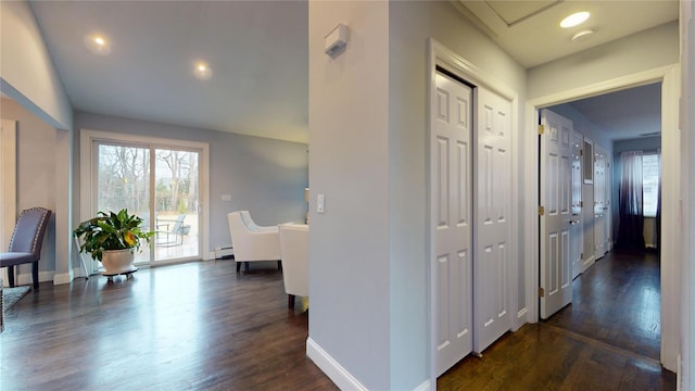 hallway featuring plenty of natural light, baseboard heating, baseboards, and dark wood-style flooring