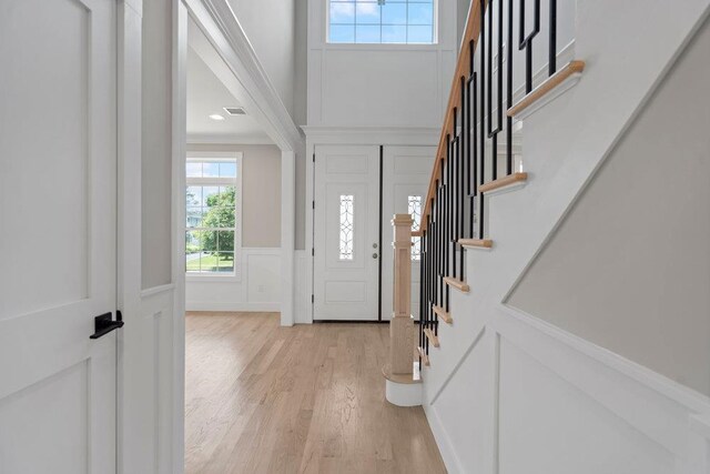 407 Wellington Rd, East Meadow, NY 11554 - foyer with light wood finished floors, stairway, a decorative wall, wainscoting, and ornamental molding