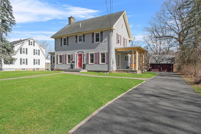 view of front of house featuring an outdoor structure, a detached garage, a front yard, and a chimney