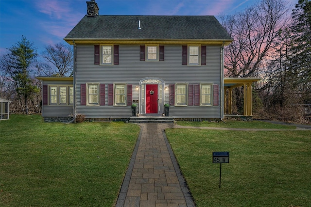 colonial home featuring a yard and a chimney