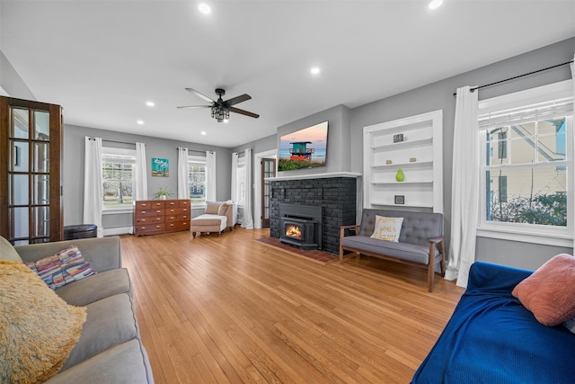 living room featuring recessed lighting, built in shelves, light wood finished floors, a ceiling fan, and baseboard heating