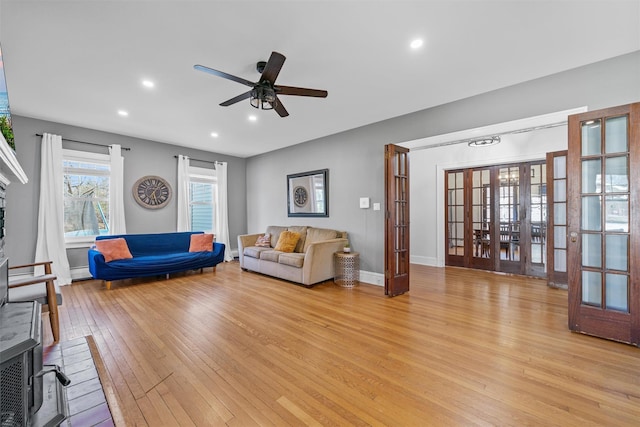 living area with recessed lighting, baseboard heating, a ceiling fan, light wood-style floors, and french doors