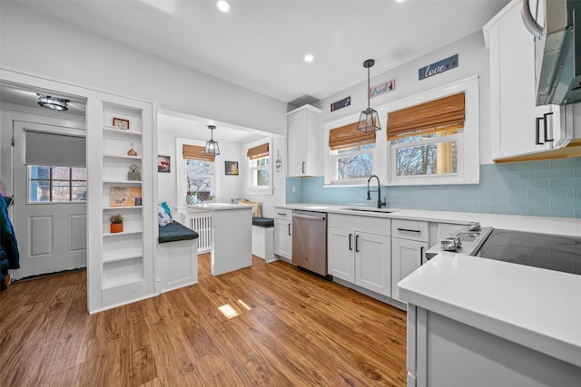 kitchen featuring white cabinets, a sink, wood finished floors, and dishwasher