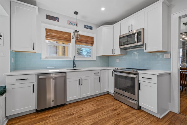 kitchen featuring light countertops, a sink, stainless steel appliances, and light wood finished floors
