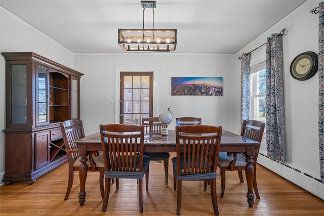 dining space with light wood-type flooring, crown molding, and baseboard heating