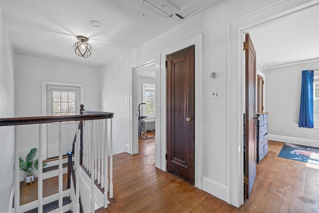 hallway featuring hardwood / wood-style floors, attic access, an upstairs landing, and baseboards