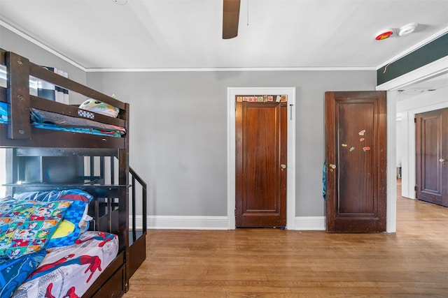 bedroom with baseboards, crown molding, wood finished floors, and ceiling fan