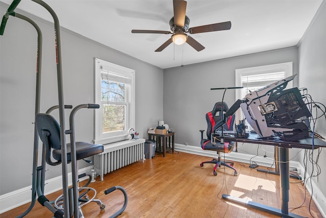 exercise room featuring baseboards, ceiling fan, radiator, and hardwood / wood-style flooring
