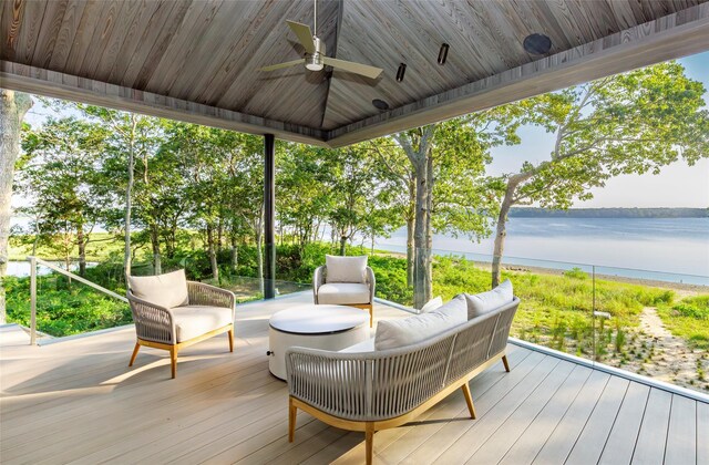 deck with a water view, outdoor lounge area, and ceiling fan