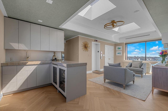 31 Casino St Ph, Ph, Freeport, NY 11520 - kitchen featuring a tray ceiling, a sink, a skylight, a peninsula, and open floor plan