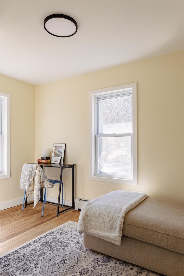 bedroom featuring baseboards, wood finished floors, and a baseboard radiator
