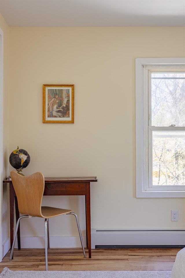 interior space featuring wood finished floors, a healthy amount of sunlight, and a baseboard radiator