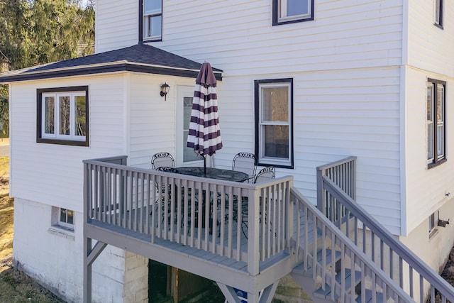 back of property with a shingled roof, stairway, and a deck