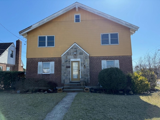 view of front of house featuring brick siding, stone siding, and a front lawn