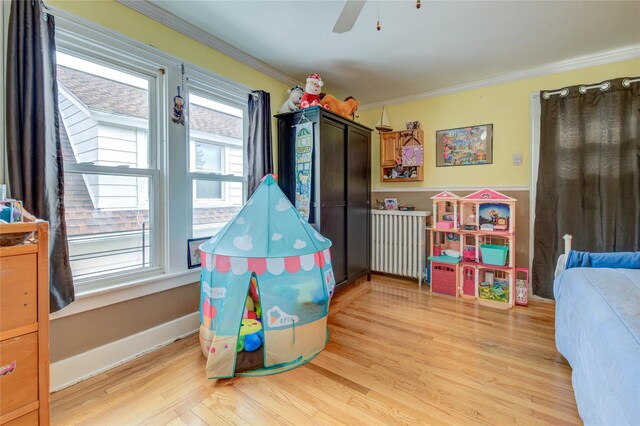 recreation room with ceiling fan, crown molding, and light wood finished floors