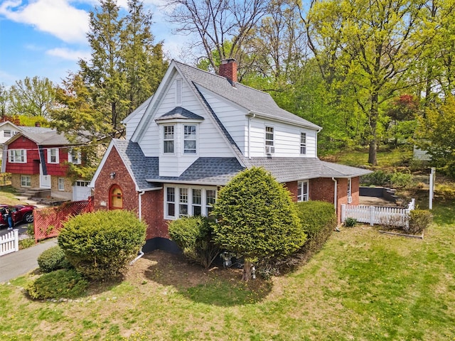 view of front of property featuring a front yard, roof with shingles, a chimney, and brick siding