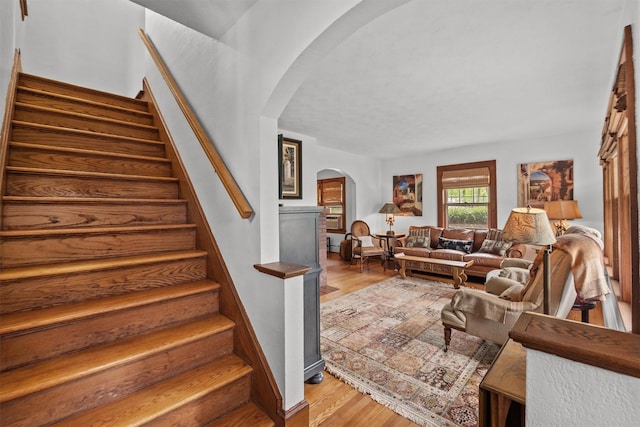staircase with arched walkways and wood finished floors