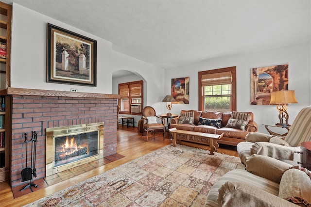 living room featuring a fireplace, wood finished floors, and arched walkways