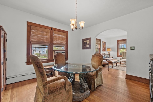 dining room with a baseboard heating unit, an inviting chandelier, baseboards, arched walkways, and wood finished floors