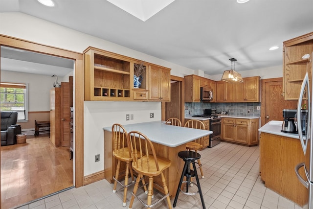 kitchen featuring a breakfast bar area, open shelves, appliances with stainless steel finishes, brown cabinets, and a peninsula