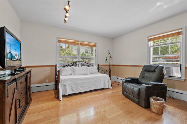 bedroom with cooling unit, light wood-style flooring, and a baseboard radiator