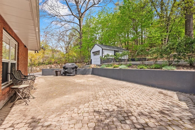 view of patio / terrace with fence, grilling area, an outbuilding, and decorative driveway