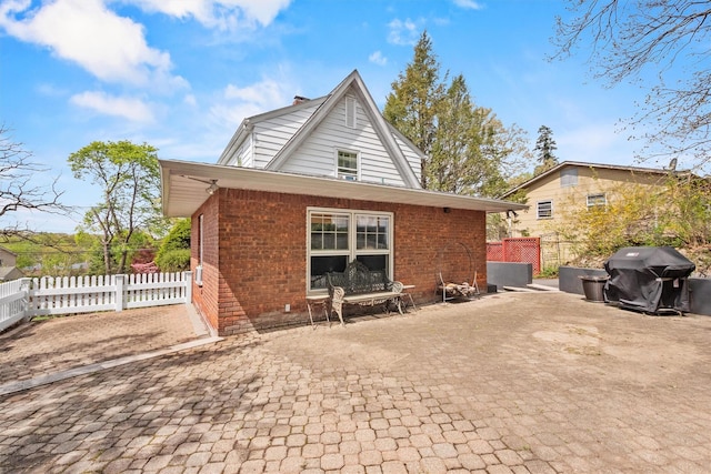 rear view of property featuring fence, a patio, and brick siding