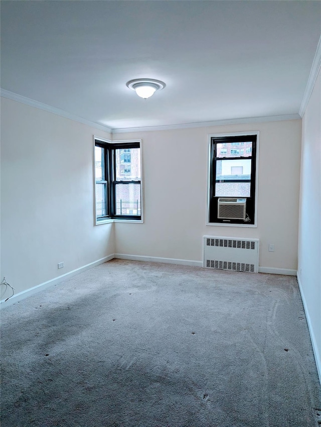 carpeted empty room with crown molding, baseboards, radiator heating unit, and a wealth of natural light
