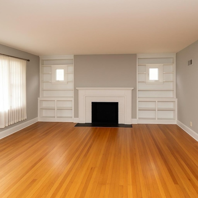 26 Alden Rd, Poughkeepsie, NY 12603 - unfurnished living room with built in features, a brick fireplace, and light wood-style flooring