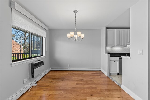 unfurnished dining area with an inviting chandelier, a baseboard radiator, light wood-style floors, and an AC wall unit