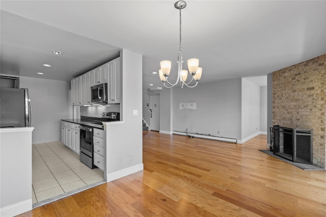 kitchen with appliances with stainless steel finishes, light wood-type flooring, a baseboard heating unit, open floor plan, and white cabinetry