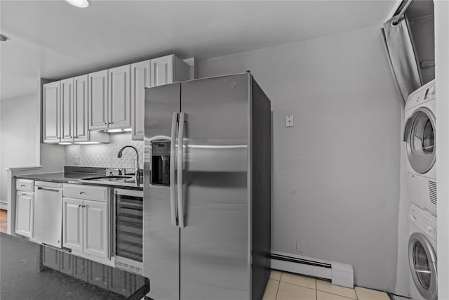 kitchen featuring stacked washer and dryer, appliances with stainless steel finishes, a sink, a baseboard radiator, and wine cooler