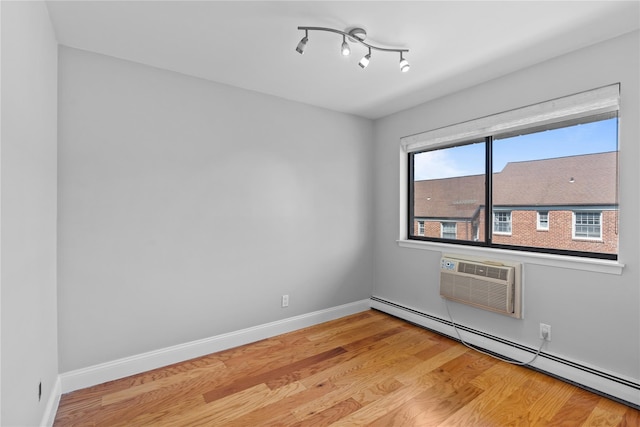 spare room with light wood-style floors, baseboards, a wall mounted AC, and a baseboard heating unit
