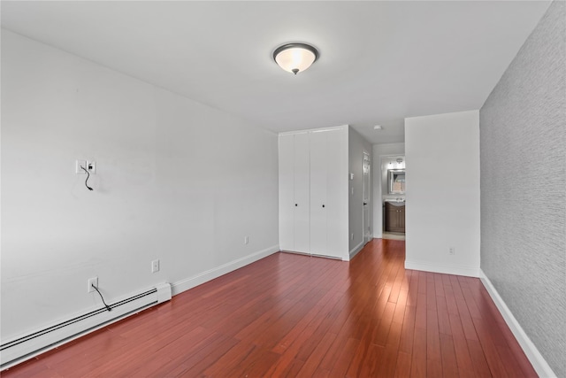 unfurnished room with baseboards, a baseboard radiator, and hardwood / wood-style flooring