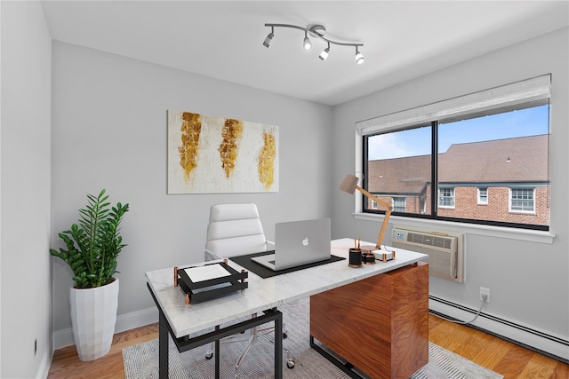 home office with baseboards, a wall mounted AC, baseboard heating, and light wood-type flooring