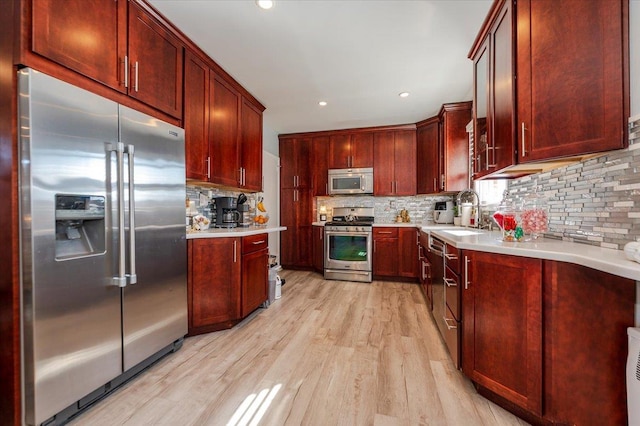 1075 Frances Dr, Valley Stream, NY 11580 - kitchen featuring appliances with stainless steel finishes, reddish brown cabinets, light wood finished floors, light countertops, and backsplash