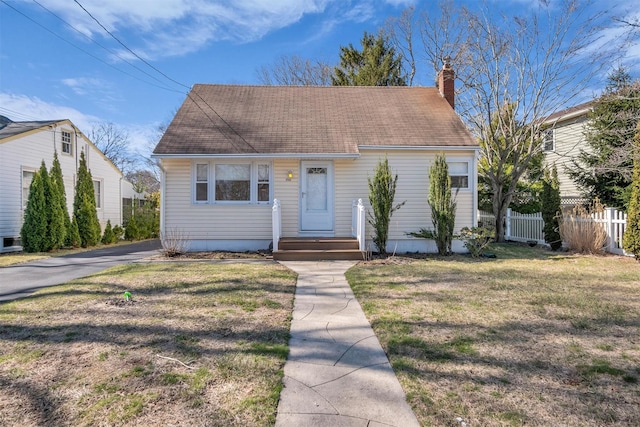 view of front of home with a front yard, a chimney, and fence