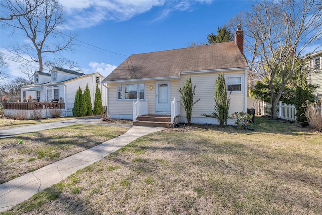 view of front facade with a chimney, a front yard, and fence